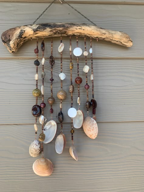 The shells for this mobile were collected on Sanibel Island, a heavenly spot for shell collectors. A multi-toned piece of driftwood from the Pacific Northwest shoreline anchors eight strands of beads. Shells have been thoroughly cleaned and lightly varnished. Beads are glass, bone and resin.  From the top of the chain hanger to the lowest shell is 17 inches and the driftwood is 14 inches wide.  This mobileis hung on sturdy wire and is suitable for indoors or outdoors, just be sure to bring it in during inclement weather. Shell And Driftwood Crafts, Driftwood And Beads, Shell Hanging Decor, Shell Chimes, Shell Hanging, Sanibel Shells, Seashell Wind Chimes, Driftwood Ideas, Driftwood Mobile