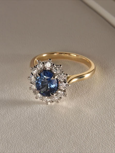 A stunning bespoke piece, set with a blue sapphire surrounded by a star shaped diamond halo. Set in platinum, enhancing the the brilliance of the white diamonds. Accompanied by a swept up yellow gold band. Engagement Rings Sapphire Halo, Silver Blue Engagement Ring, Sapphire Diamond Rings Engagement, Gold Ring With Blue Sapphire, Sapphire Engagement Ring Gold Band, Diamond Engagement Ring With Sapphires, Blue Sapphire Gold Ring, Blue Gold Ring, Coloured Engagement Rings Vintage