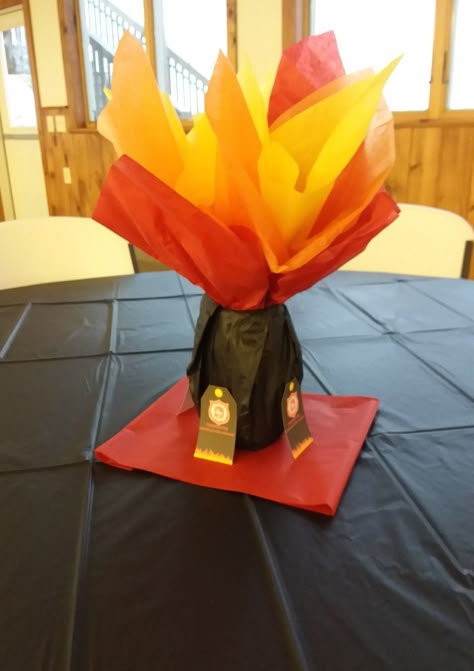 Decoration for fire department dinner. Cover Mason jars with black tissue paper.  Make the fire with red, orange, and yellow tissue paper.  Thank you cards standing against the jar.  Black tablecloth to pop the color. Fire Department Decorations Parties, Firefighter Table Decorations, Fire Banquet Centerpieces, Fire Decorations Party, Fire Truck Party Centerpieces, Fire Truck Centerpiece Ideas, Firefighter Birthday Party Centerpieces, Fire Department Party, Fire Department Banquet Decorations