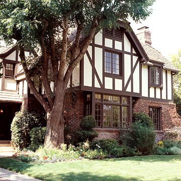 Steeply pitched gable roofs, artfully detailed masonry chimneys, clustered windows, and grand entryways generally make Tudor homes easy to recognize. Elaborate brick or stonework on the first story is usually accompanied by decorative half-timbering, or exposed wood framework, with the spaces between the timbers filled with stucco./ German Tudor Style Homes, Tudor Garage, Tudor Exterior, Tudor House Exterior, Tudor Houses, English Tudor Homes, Tudor Homes, Stucco Siding, Mission Style Homes