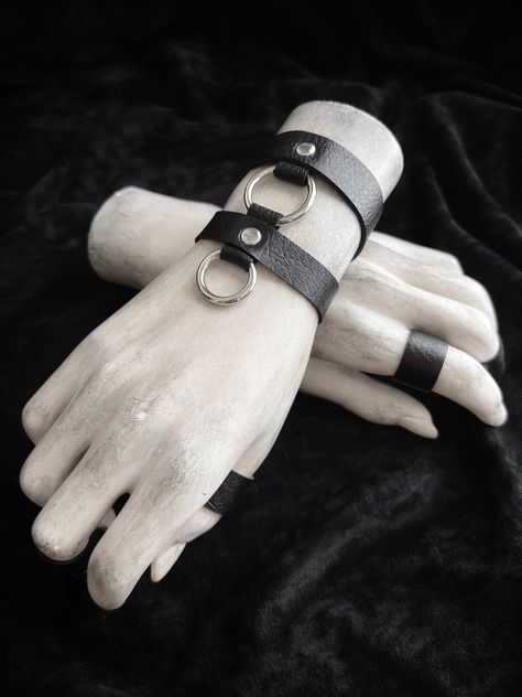 "Dual band linked black cuff bracelet with silver accents. ~ jet black arm bands made from faux vegan leather ~ save $ by stocking up! layer your pieces on one arm or both ~ upper band: 5/8\" wide - lower band: 1/2\" wide | middle o-ring: 1\" wide - drop o-ring: 7/8\" wide ~ adjustable slider with hook closure ~ bands are secured with silver rivets, and have black nylon coated metal hardware ~ made-to-order: please measure your wrist circumference, and choose from the options in the drop down me Punk Wrist Cuffs, Goth Armor, Arm Band Design, Goth Bracelets, Armor Jewelry, Black Cuff Bracelet, Bracelet Cuffs, Leather Wrist Cuff, Harness Fashion