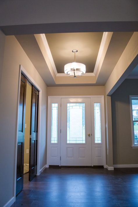 Front entry way and foyer with modern light fixture and tray ceilings - custom home by Carriage Manor Tray Ceiling Entryway, Foyer Ceiling Ideas Entryway, Tray Ceiling Foyer, Foyer Ceiling Ideas, Foyer Lighting Low Ceiling, Modern Hall, Home Gym Design Garage, Entrance Lighting, Low Ceiling Lighting