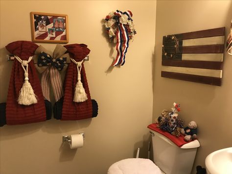 Americana bathroom decor. Top of commode, I just used a red napkin & folded it in half with a wire basket that has a piece of blue with stars material inside. The candle I bought from Cracker Barrel store and put red, white and blue rocks/marbles around it inside the wire basket. Americana Bathroom Ideas, 4th Of July Bathroom Decor, Americana Bathroom Decor, Patriotic Bathroom, Americana Bathroom, Cracker Barrel Store, Blue Rocks, Americana Crafts, Red Napkins