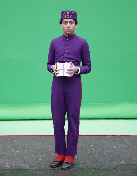 Tony Revolori as Zero, standing in front of a green screen, Mendl’s box in hand | The Grand Budapest Hotel Zero The Grand Budapest Hotel, Zero Grand Budapest Hotel, Wes Anderson Green, Grand Budapest Hotel Costume, Grand Budapest Hotel Book, Wes Anderson Book, Wes Anderson Characters, Tony Revolori, Wes Anderson Aesthetic