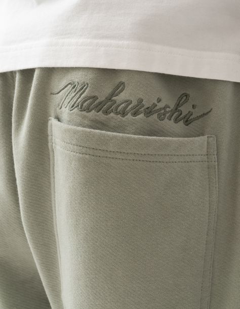 Relaxed-fit organic cotton sweatpants in sage, complete with ribbed cuffs and a drawstring waist for adjustment. Features a tonal Maharishi Script embroidery above back patch pocket. Maharishi’s Sage draws inspiration from vintage military fatigues, referencing the faded green shade of classic U.S. Air Force uniforms. The colour is doubly significant thanks to the spiritual value of sage itself, which is widely viewed to represent purification and etheric protection; the plant is revered across Sweatpants Design, Clothing Branding Design, Sports Day Outfit, Air Force Uniforms, Script Embroidery, Spiritual Clothing, Fashion Poster Design, Organic Aesthetic, Fashion Embroidery