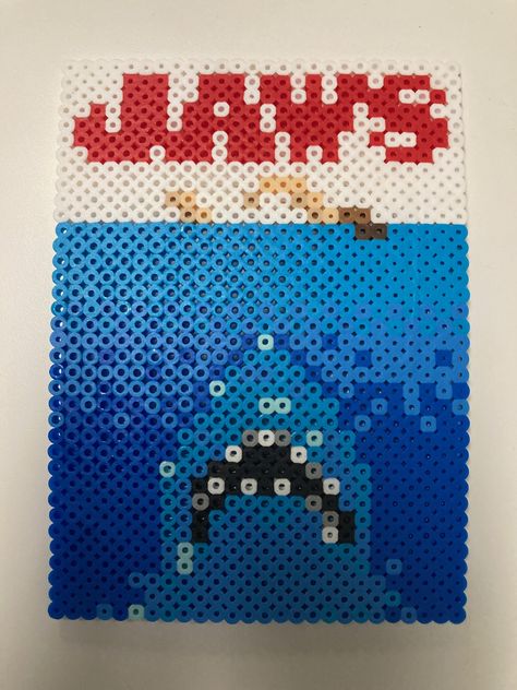 A Perler bead pattern of the Jaws movie poster. 

 Perler bead art, Perler bead patterns, Perler bead ideas, Perler beads, pixel art, Perler bead projects, Jaws Jaws Pixel Art, Perler Bead Movie Poster, Fish Perler Beads, Movie Perler Beads, Jaws Movie Poster, Ironing Beads, Melt Beads Patterns, Melt Beads, Jaws Movie