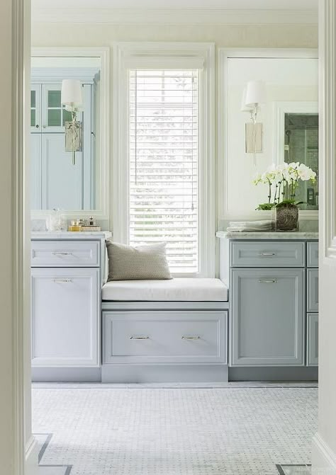 Gorgeous bathroom features a a built-in window seat with drawer flanked by separate vanities fitted with blue gray cabinets adorned with nickel hardware topped with gray and white marble under white beveled vanity mirror illuminated by Hudson Valley Lighting Glenford Sconces alongside marble basket weave tiled floor accented with gray border tiles. Blue Bathrooms Designs, Built In Window Seat, Vanity Seat, Guest Bathroom Remodel, Bathroom Window, Bathroom Remodel Pictures, Small Remodel, Transitional Bathroom, Gorgeous Bathroom