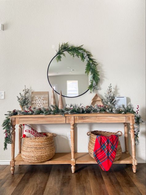 Christmas entryway table round mirror garland holiday season decorations Garland On Entry Table, Entry Table Garland, Christmas Entry Way Ideas, Small Entryway Table Christmas Decor, Christmas Entryway Mirror Decor, Xmas Entry Table Decor, Whimsical Christmas Entry Table, Round Mirror Christmas Decor, Everett Foyer Table Christmas