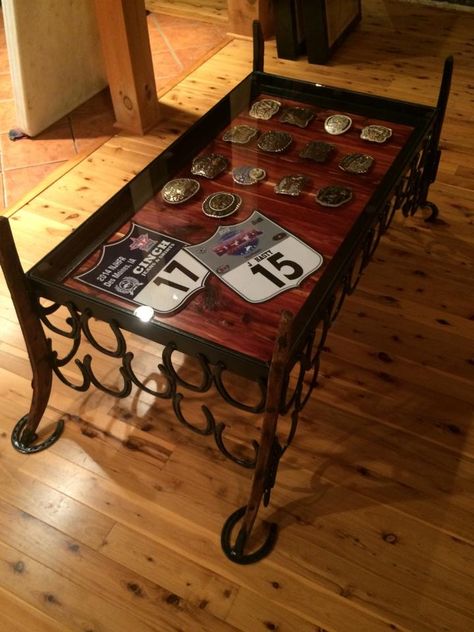 Display coffee table; horseshoes, harness hames, and cedar GAW-JUSSSSSX Trophy Saddle Display, Belt Buckle Display Coffee Table, Rodeo Back Number Display, Horseshoe Furniture, Western Ranch Home Decor, Shipping Container Shop, Saddle Room, Rodeo Awards, Horseshoe Table