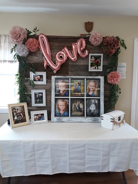 Barnboard wall used as a backdrop for a bridal shower gift table with family photos, tissue paper pompoms, willow branches, rose gold love balloon. Bridal Shower Display Table, Gift Table Backdrop Ideas, Wedding Shower Pallet Ideas, Couple Shower Backdrop, Wedding Shower Picture Backdrop, Bridal Shower Head Table, Easy Bridal Shower Backdrop, Wood Pallet Bridal Shower Ideas, Bridal Shower Gift Table Ideas