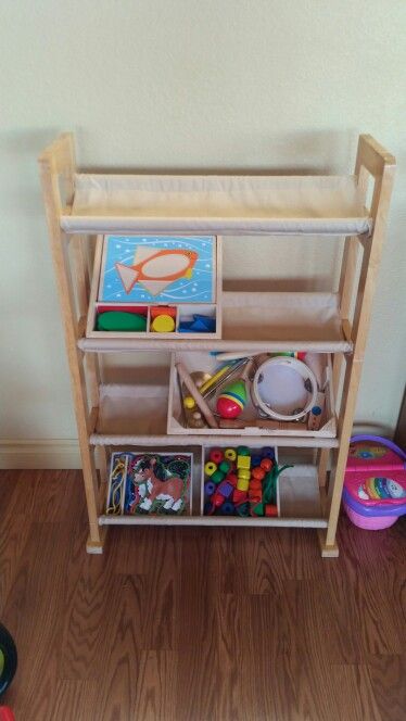 Repurposed an old VHS/media rack by taking apart and sewing in fabric shelf liners. Keeps them organized, but also still in view to catch the interest of little eyes. I didn't want to stack them on the shelf to be forgotten. Diy Toy Bin, Dvd Shelf Repurpose, Vhs Case Repurpose, Vhs Shelf, Repurpose Toy Bin Organizer, Upcycle Dvd Cases, Upcycle Dvd Rack, Toy Rack, Media Rack