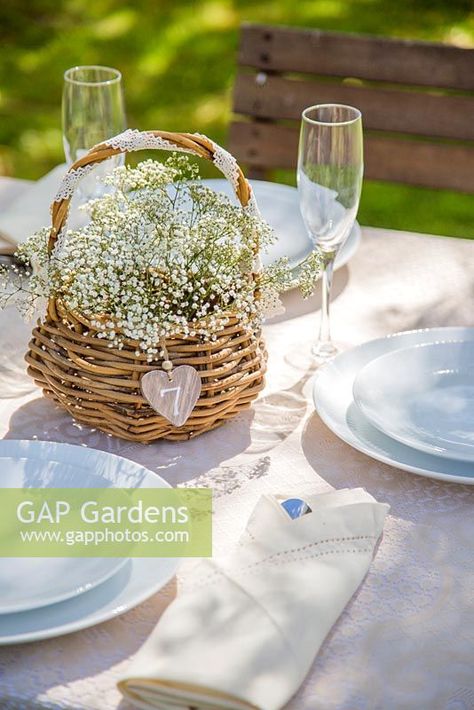 Wicker basket of Gypsophila used as a table setting. Basket Of Flowers Centerpiece, Simple Garden Birthday Decor, Wicker Basket Centerpiece Ideas, Basket Wedding Centerpieces, Picnic Basket Flower Arrangement, Basket Centerpieces Table Wedding, Flower Basket Centerpieces, Wicker Wedding Decor, Basket Centerpieces Table