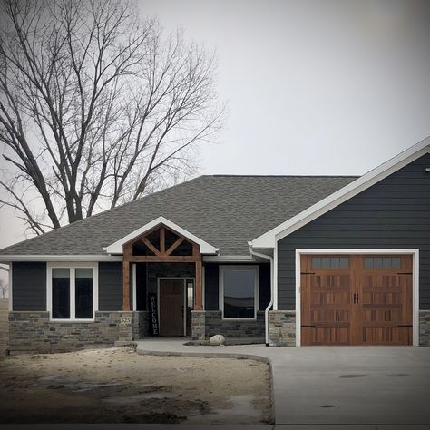 Stone Siding Exterior Ranch Style, Farmhouse Exterior Ideas Stone, Black Metal Roof Dark Grey Siding, Gray House With Rock Exterior, Tan House With White Windows, Navy House With Wood Accents, Dark Grey Siding With Stone, Stone Exterior Ranch Style Home, White House Black Trim Stone Accent