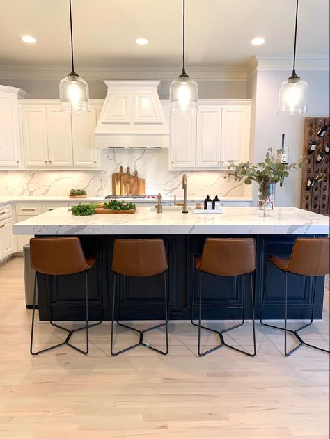 Kitchen with white cabinets, blue island, brass hardware, wood accents, and metal & leather barstools. Designed by L Reaves Interiors. #LRIdesign #LReavesInteriors #kitchen #blueisland #quartzcounter #barstools Navy Blue Island With Bar Stools, Kitchen With Dark Island And White Cabinets, Blue Accent Kitchen Island, Colored Kitchen Island With White Cabinets, White Cabinet With Navy Blue Island, White Kitchen With Barstools, Kitchen Island Dark Blue, White Kitchen Navy Blue Island Gold Hardware, White Kitchen With Dark Blue Island