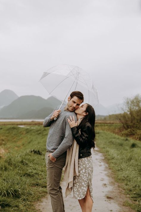 Couple getting cozy in the rain with a clear umbrella while she is kissing him on the cheek. Vancouver Photoshoot, Umbrella Photoshoot, Rainy Photoshoot, Rainy Engagement Photos, Rainy Wedding Photos, Rainy Photos, Rainy Day Photos, Rainy Day Photography, Umbrella Photography