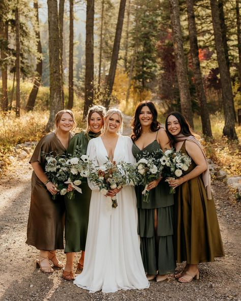 Bride and bridesmaids stand close together smiling at camera Boho Fall Wedding Bridesmaid Dresses, Green Wedding Family Photos, Bridesmaids In Different Shades Of Green, Fall Wedding Olive Green, Green And Brown Bridesmaid Dresses, Mix Match Bridesmaid Dresses Fall, Forest Wedding Bridesmaid Dresses, Brown And Green Wedding, Earthy Wedding Colors