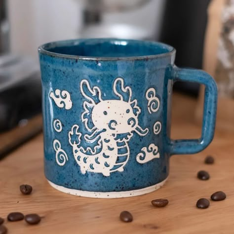 A little dragon appears! After many months of research, design, and making, the first ceramic pieces of my dragon collection will become available April 26. The majority of the work will be this 400 ml mug, along with a few other designs, and maybe even a few dragon plates too. With 3 weeks left, there's still a lot to do - but I can't keep putting off the release! Besides, I plan to continue adding to this collection for the entire year anyway :) Which means I also have the rest of the ye... Dragon Pottery Painting, Drawing On Pottery, Mug Designs Painted, Cup Designs Ideas, Painting Ceramics Ideas, Dragon Ceramics, Dragon Pottery, Ceramic Dragon, Dragon Plate