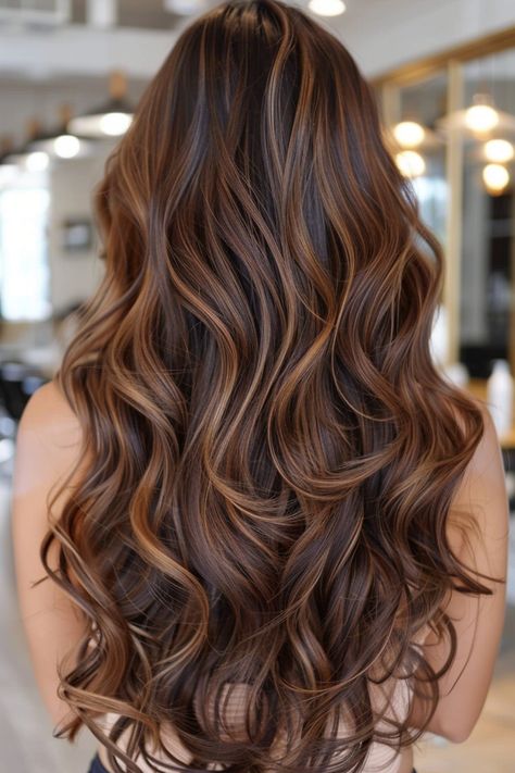 Long, wavy hair with rich brown and caramel highlights in a salon setting. Blonde Hair Brown Highlights Caramel, Dark Golden Balayage, Caramel Highlights On Dark Hair Wavy, Brown Carmel Balayage Hair, Dark Brown Hair Balayage Auburn Caramel Highlights, Carmel Red Blonde Balayage, Golden Brunette Highlights, Cooper Caramel Hair, Dark Hair Honey Highlights