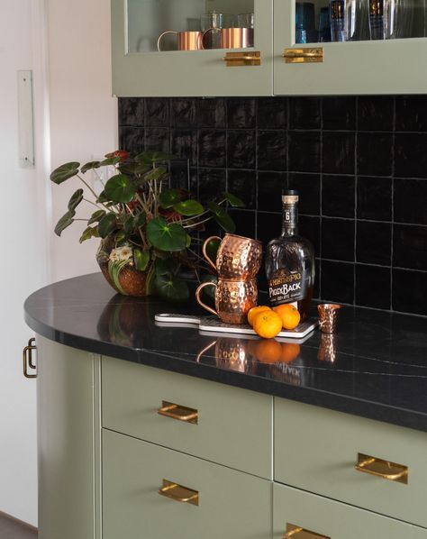 🌿✨ This sage green cabinetry with brass handles paired with a sleek black backsplash adds both style and functionality to the kitchen. Perfect spot for a morning coffee or evening cocktail! ☕🍹 Design by @zenithdesignbuild Photos by @goldenphotosdsm #KitchenInspo #ModernKitchen #SageGreen #InteriorDesign #HomeDecor #BrassAccents #CoffeeCorner Dark Green Backsplash Kitchen, Green And Black Kitchen Ideas, Sage Green And Black Kitchen, Black And Green Kitchen, Green And Black Kitchen, Green Backsplash, Cocktail Design, Black Backsplash, Coffee Corner