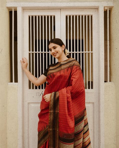 மல்லி In a Pattu pett saree Soft shades or vibrant hues might dominate the saree palette, reflecting the mood of a casual day. Patterns could include simple checks, stripes, or floral designs, adding a touch of charm without overwhelming the overall look. This stunning red Kanchipuram silk saree features a vibrant black silk border and a classic checkered pattern on the body. [Silk, Pattu Pet, Tulsi Weaves, silk saree, saree, silk, handloom saree, handloom, Traditional, Vintage, No Zari, K... Checks Saree, Saree Silk, Saree Handloom, Kanchipuram Silk Saree, Checkered Pattern, Handloom Saree, Floral Designs, The Mood, Black Silk