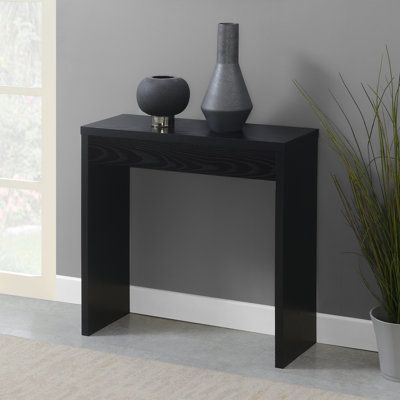 This minimalist piece effortlessly combines functionality and aesthetics, making it the perfect focal point for your home. Whether you want to enhance your entryway, hallway, front corridor, foyer, living room, or any space in need of a refresh, this versatile table is the ideal choice. The spacious tabletop offers ample room to display elegant decor and collectibles. Its simple yet modern design ensures it fits snugly in narrow spots while maintaining a spacious feel. Crafted from manufactured Small Entry Way Table Modern, Black Console Tables, Black Console Table Entryway, Apartment Foyer Design, Small Hallway Table, Small Entryway Decor, Small Black Table, Black Entryway, Small Entryway Table