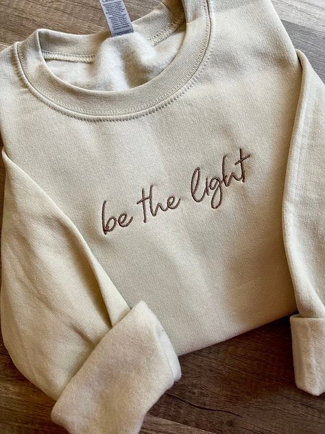 Embroidered "be the light" crewneck sweatshirt,  *custom wording is available : make heaven crowded, faith over fear, walk by faith, wait.pray.trust, made new, etc...! * list your wording in personalization option - check spelling , please no long words as that will effect size of embroidery and include thread color ( font will remain same as shown in main image )!    🧵 THREAD COLORS available : white, black, brown, sand, taupe, golden pecan, charcoal grey, silver grey,  teal, sage, mauve, dark Long Words, Make Heaven Crowded, Faith Sweatshirt, Jesus Clothes, Brown Sand, Be The Light, Walk By Faith, Christian Clothing, Christian Shirts