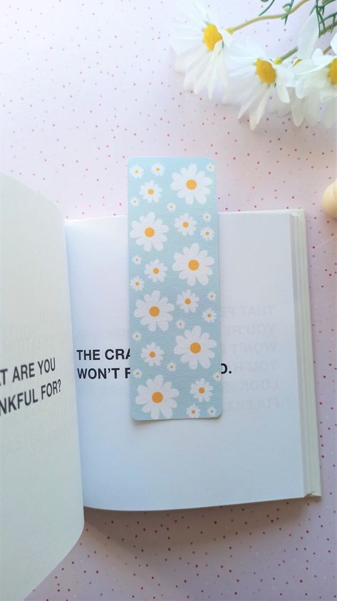 Beautiful daisy flower bookmark with a pastel blue background. Keep track of your reading with this gorgeous illustrated bookmark. Printed on cardstock 180 gsm and laminated for protection and gloss. You can choose between a simple bookmark or with tassel! *The design is on both sides! For similar items, check the link here: https://www.etsy.com/dk-en/shop/CraftachicDesigns?section_id=31617264 Packaging Materials: glassine paper bag Size approx: 14x4.5 cm (simple)                        26x4.5 c Blue Bookmark Ideas, Design For Bookmarks, Preppy Bookmarks, Simple Bookmark Design, Pastel Bookmarks, Bookmarks Design, Pretty Bookmarks, Daisy Bookmark, Book Bookmarks