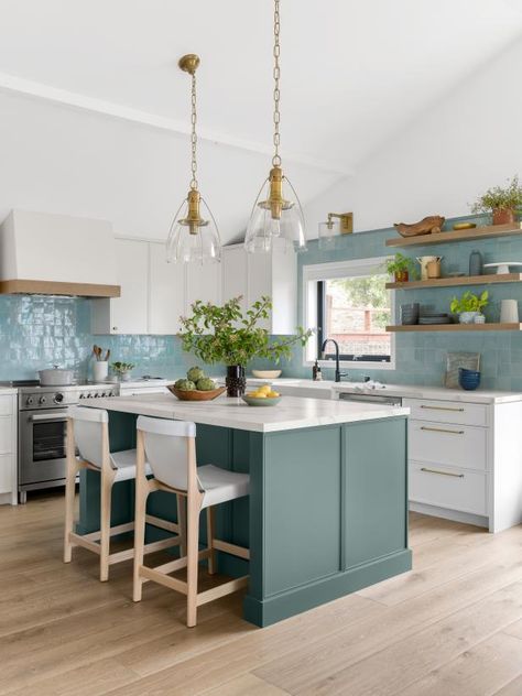 Mary Jo originally suggested these shimmery backsplash tiles from Clé in white, but when Katherine saw them in light blue, she was smitten. “The coloring varies and there are little chips and cracks because they’re handmade,” she says. Natural wood accents, like the open shelves and CB2 stools, nod to the house’s former life as a cabin. The pendants are from Visual Comfort. Seafoam Island Kitchen, White Blue And Wood Kitchen, Coastal Green Kitchen, Shimmery Backsplash, Teal Kitchen Backsplash, Coastal Grandma Kitchen, Beachy Kitchen Backsplash, White Kitchen Blue Backsplash, Coastal Kitchen Ideas Seaside