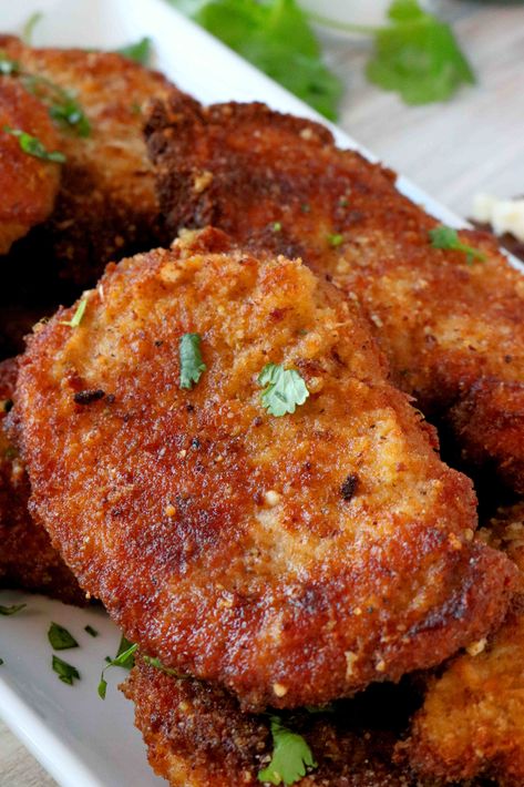 A close up shot of Parmesan Crusted Pork Chops with parsley sprinkled over the top. Parmesan Crusted Pork Loin, Parmasean Crusted Pork Chop, Garlic Crusted Pork Chops, Extra Crispy Pork Chops, Parmesan Fried Pork Chops, Pablo Crusted Pork Chops, Top Loin Pork Chops, What Sides Go With Pork Chops?, Pork Parmesan Recipe