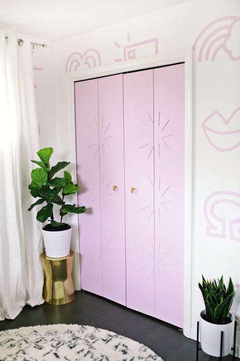 Swap out-dated accordion doors for new flat panel doors and fresh hardware. A Beautiful Mess creates a pretty focal point in this nursery. She elevates the plain doors with a pop of paint and unique trim. Closet Door Diy, Diy Closet Door, Custom Closet Doors, Pink Doors, Sliding Mirror Closet Doors, Diy Closet Doors, Closet Door Makeover, Closet Built Ins, Beautiful Closets