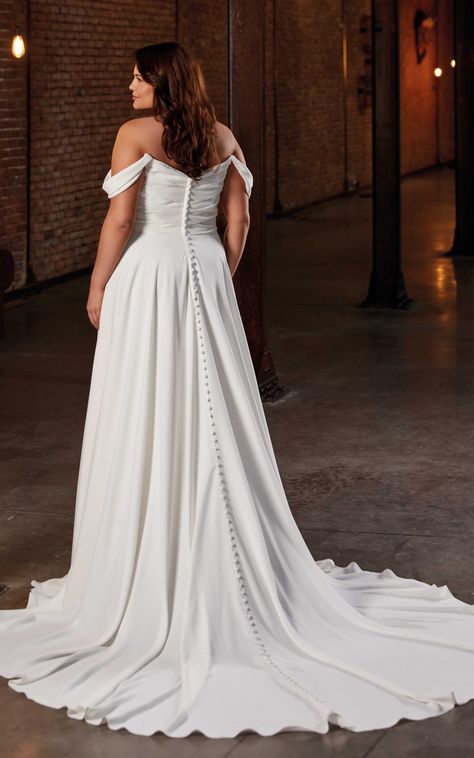 ELSIE is an A-Line gown in ivory Crepe with a ruched bodice, pockets, and buttons to the end of the train.