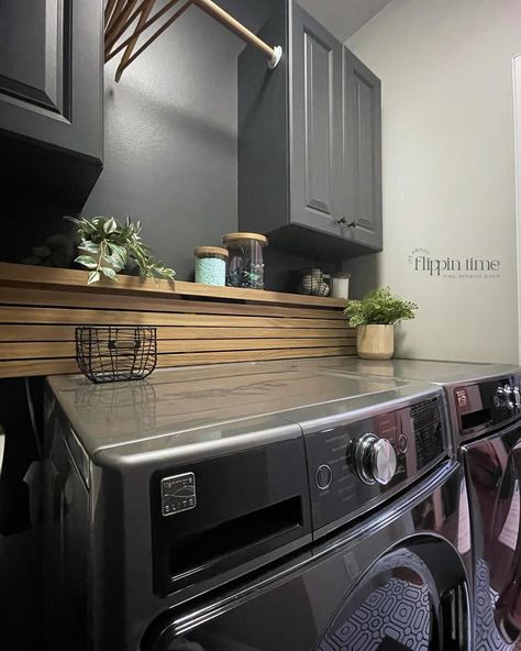 Incredible transformation in just two days! The decision to paint the walls ‘Iron Ore’ from @sherwinwilliams was spot on—it adds a dramatic and modern vibe. The sleek wood slat panel is a perfect way to hide the washer and dryer hookups, and it complements the bold geometric flooring perfectly. This laundry room makeover is seriously one of my favorites. #LaundryRoomMakeover #HomeTransformation #IronOre #SherwinWilliams #ModernDesign #DIYHome #InteriorInspo #LaundryRoomGoals #furnitureartis... Hide Water Lines In Laundry Room, How To Hide Washer And Dryer Hookups, Hide Washer Dryer Hookups, Black And Wood Laundry Room, Shelf To Hide Laundry Hookups, How To Cover Washer And Dryer Hookups, Dark Grey Laundry Room, How To Hide Washer Dryer Hookups, Hide Washer And Dryer Hookups