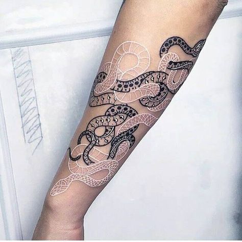 Two intertwined snakes tattoo on the left forearm