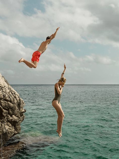 Side view of couple in swimsuit jumping from rock into clean water of ocean lagoon. Attention: models are in a slight motion blur Couple Jumping Into Water, Jumping Into Water Aesthetic, Man And Woman Aesthetic, People Jumping Into Water, Jump Into Water, Jumping People, Jumping Into Water, Person Swimming, Woman Jumping