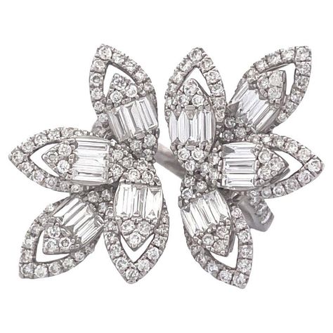 Enhance your style with this stunning 18k white gold diamond ring featuring a unique four-leaf cluster design on both ends. The ring boasts a total of 146 brilliant round cut diamonds, totaling 0.94 carats, beautifully arranged in clusters. Additionally, it showcases 24 mesmerizing baguette diamonds, totaling 0.74 carats, adding a touch of sophistication. With a total weight of 8.2 grams, this ring exudes elegance and charm. Size 6.5 Selling Price: $ 4000.00 Cocktail Ring Designs, Fancy Diamond Ring, Cluster Design, Diamond Cocktail Ring, Gold Ring Designs, Diamond Cocktail Rings, Gold Diamond Ring, White Gold Diamond Rings, Gold Diamond Rings