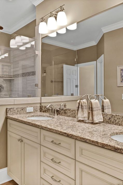 Warm earth-toned primary ensuite bathroom with cream cabinets and granite vanity top. Bathroom Cream Cabinets, Tan Vanity Bathroom, White Cabinet Brown Granite, Cream Bathroom Cabinets, Brown Bathroom Tile Ideas, Cream And Brown Bathroom, Tan And White Bathroom, Cream Bathroom Vanity, Brown Bathroom Tile