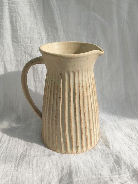 Hand thrown in my UK ceramics studio, and carved with elegant vertical grooves. Made from a lovely flecked stoneware clay, and glazed in a satin oatmeal glaze. 17cm tall and fully functional. Pottery Ideas For Beginners Wheel, Ceramic Throwing Ideas, Wheel Throwing Pottery Ideas, Beginner Pottery Hand Building, Thrown Pottery Ideas, Pottery Functional, Wheel Thrown Pitcher, Pitcher Design, Hand Built Pottery Jug