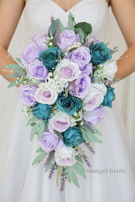 This lovely assortment of is bound to turn heads on your wedding day. This lovely cascading brides’ bouquet from the is an absolutely breathtaking arrangement for any bride to be, in any season. This bouquet is made with lavender roses, lavender center roses, and teal roses accented with greenery This bouquet is 10” wide, 18” long, and is crafted by our in-house florists without using a foam base to anchor the flowers to the bouquet. Instead, we wire our bouquets by hand so that we can further e Teal Lavender Wedding, Blue Purple White Wedding Bouquet, Lilac And Turquoise Wedding, Pastel Rainbow Wedding Flowers, Mint Green And Purple Wedding Theme, Purple And Aqua Wedding, Lilac And Sky Blue Wedding, Teal And Lilac Wedding, Lavender And Turquoise Wedding