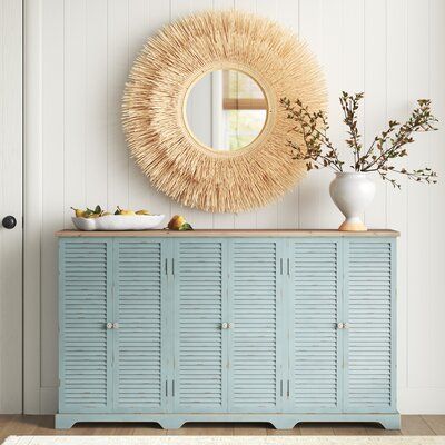 This sideboard showcases a distressed sea green finish that creates a coastal farmhouse accent in your dining room or living room. It's made from solid fir and engineered wood with a natural-finished top for a breezy hint of contrast. The three double-door cabinets have louvered doors that add eye-catching farmhouse detail and are open to reveal two fixed shelves in each where you can keep your server or barware. Plus, this buffet table arrives fully assembled. | Sand & Stable™ Ocala 63" Wide Wo Coastal Dining Room Cabinet, Coastal Dining Room Sideboard, Coastal Chic Furniture, Pacific Coastal Decor, Coastal Chic Dining Room Table, Coastal Media Console, Coastal Entry Table Decor, Contemporary Beach House Decor, Coastal Farmhouse Nursery