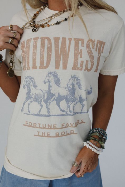 No boho closet is complete without the perfect graphic tee, and the Midwest Fortune Graphic Tee is it! So cool, you won’t want to miss out! Comfortable, mineral-washed, Cotton tee shirt fabric Relaxed and slouchy silhouette for ultimate comfort Classic crew neckline with dropped shoulders and loose short sleeves So cool Western Inspired Running Wild Horses with 'MIDWEST - Fortune Favors the Bold' Graphic Pair with: Eye Of The Sun Padded Bralette, The Signature Flare and Shoreline Platform Sandal Boho Closet, Boho Essentials, Fortune Favors The Bold, Bralette Outfit, Padded Bralette, Moon Collection, Trendy Graphic Tees, Boho Shirts, Loose Shorts