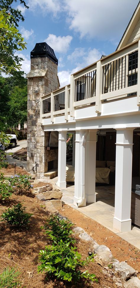 Just completed this beautiful deck with 10x10 white pvc columns below. The deck features a dry undeck system and a paver patio below the deck. There are also two gas fireplaces, one on each level with a massive natural stone chimney. Deck With Stone Skirting, Houses With Chimneys Exterior, Outdoor Fireplace Under Deck, Under Deck Fireplace, Fireplace Under Deck, Fireplace On Deck Outdoor, Two Story Patio, Deck With Patio Underneath, Fireplace On Porch