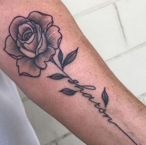 Rose tattoo with name in the stem @tessemilytattoos | Rose ... #tattooideas #rosetattoos Rose With Name On Stem Tattoo, Name As Stem Tattoo, Rose Birthday Tattoo, Flower Name Tattoo For Men, Rose Name Stem Tattoo, Tattoo Rose With Name, Rose Tattoo With Name Forearm, Flower Tattoos With Names Stems, Flower Stem Name Tattoo