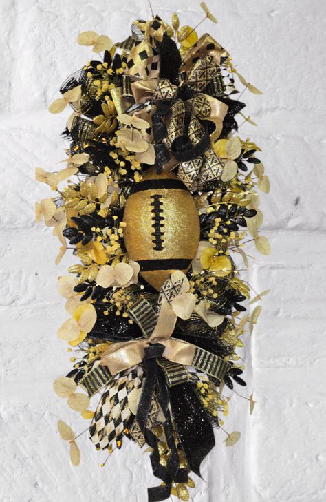 Get ready for the season with this stunning Football-Themed Fall Wreath! Perfect for football fans and game-day gatherings, this handcrafted wreath features rich black and gold hues, glittering accents, and bold ribbons, topped with a sparkling football centerpiece. Whether you're decorating your front door, porch, or game room, this wreath will add a festive touch to every kickoff. Celebrate your team spirit in style with a wreath that's as vibrant as your love for the game! Football Centerpiece, Steelers Wreath, Football Centerpieces, Football Wreaths, Football Diy, Football Wreath, Door Porch, Front Door Porch, Door Swag