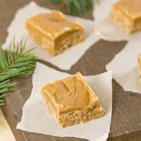 square crop of brown suagr fudge on pieces of parchment paper on a wooden background with fir tree branches