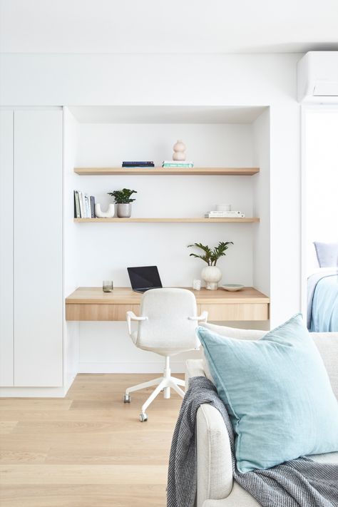 Inner-city apartment renovation showing a study nook built next to custom white joinery. The study nook features a pale timber floating desk with drawers & open timber shelving above. The shelves are styled with books, plants & ceramic items. A white office chair also sits at the desk behind an open laptop. The edge of an off-white sofa with a pale chambray blue cushion and blue-grey throw can be seen in the foreground. The master bedroom, in similar tones of blue, can be seen just out of frame. Built In Office Nook In Living Room, Open Plan Study Area, Hamptons Study Nook, Desk Alcove Built Ins, Linen Cupboard Study Nook, Study Nook Cabinetry, Study Nook In Kitchen, Built In Workspace, Study Nook In Bedroom