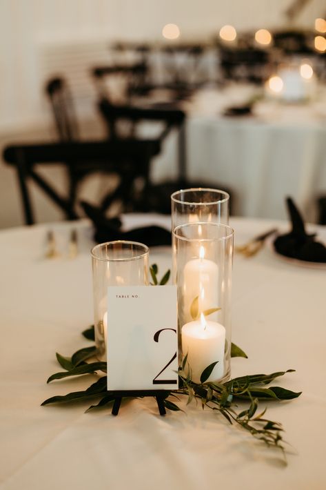 A romantic grouping of hurricane candles on top of  sprigs of greenery is a perfect touch to this elegant and modern wedding reception.

- Olivia Doerfler Photography Modern Simple Wedding Centerpieces, Minimal Candle Wedding Decor, Very Simple Wedding Centerpieces, Simplistic Table Decor Wedding, Simple Wedding Table Decor Candles, 3 Candle Centerpiece, Greenery For Wedding Tables, Candle Center Piece For Wedding Tables, Modern Simple Wedding Decor