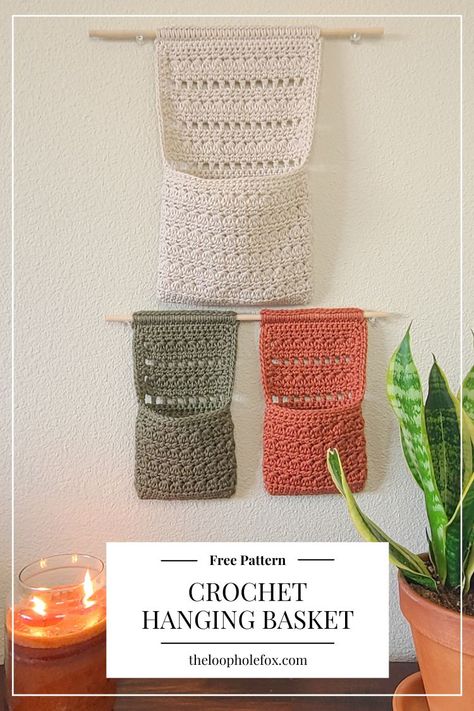 Perfect for those who like to keep things organized and have something pretty and fun to look at, The Millie Crochet Hanging Basket checks off all boxes. This pattern combines a crochet wall hanging with a pouch-like crochet basket to free up your desk or other surfaces by hanging on the wall. Hanging Storage Crochet Pattern, Crochet Projects Basket, Crochet Pattern For Hanging Basket, Crochet Book Organizer, Crochet Housewarming Gift Ideas, Crochet Hanging Pattern, Crochet Ideas For Home Decor Inspiration, Crochet Plant Wall Hanger Pattern Free, Crochet Wall Holder