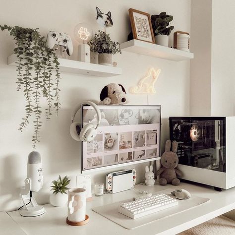 A cozy and inviting home office setup featuring a white desk with modern computer equipment, surrounded by playful decorations including plush toys, hanging plants, and unique neon light art. The walls are adorned with various shelves showcasing more plants, toys, and framed pictures, creating a warm and whimsical atmosphere. Cute Diy Decor, Cozy Desk Setup, Cute Desk Decor, Cozy Desk, Handmade Photo Frames, White Room Decor, Desk Setups, Cozy Home Office, Desk Inspiration