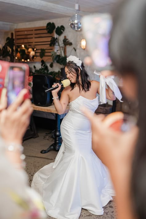 Bride wearing a strapless mermaid wedding dress with a flower headband holding microphone for karaoke wedding reception entertainment | wedding karaoke | wedding entertainment ideas | wedding games and fun | Lucie Watson Photography Karaoke Wedding Reception, Wedding Karaoke, Karaoke Wedding, Holding Microphone, Strapless Mermaid Wedding Dress, Wedding Entertainment Ideas, Reception Entertainment, Wedding Reception Entertainment, Entertainment Wedding