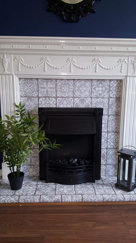 Our fireplace when I was finished! Spray painted the fire black with a heat resistant metal spray paint and bought the cutest little fake tile stickers from amazon to cover the marble from before, then finished with a spot of white gloss around the frame and it looks a million times better, all for roughly £40. Sticker Tiles Fireplace, Tile Stickers Fireplace, White Fire Surround, Tile Around Fireplace, Metal Spray Paint, Victorian Fireplace Tiles, Stove Ideas, Painted Fireplace, Victoria Gardens